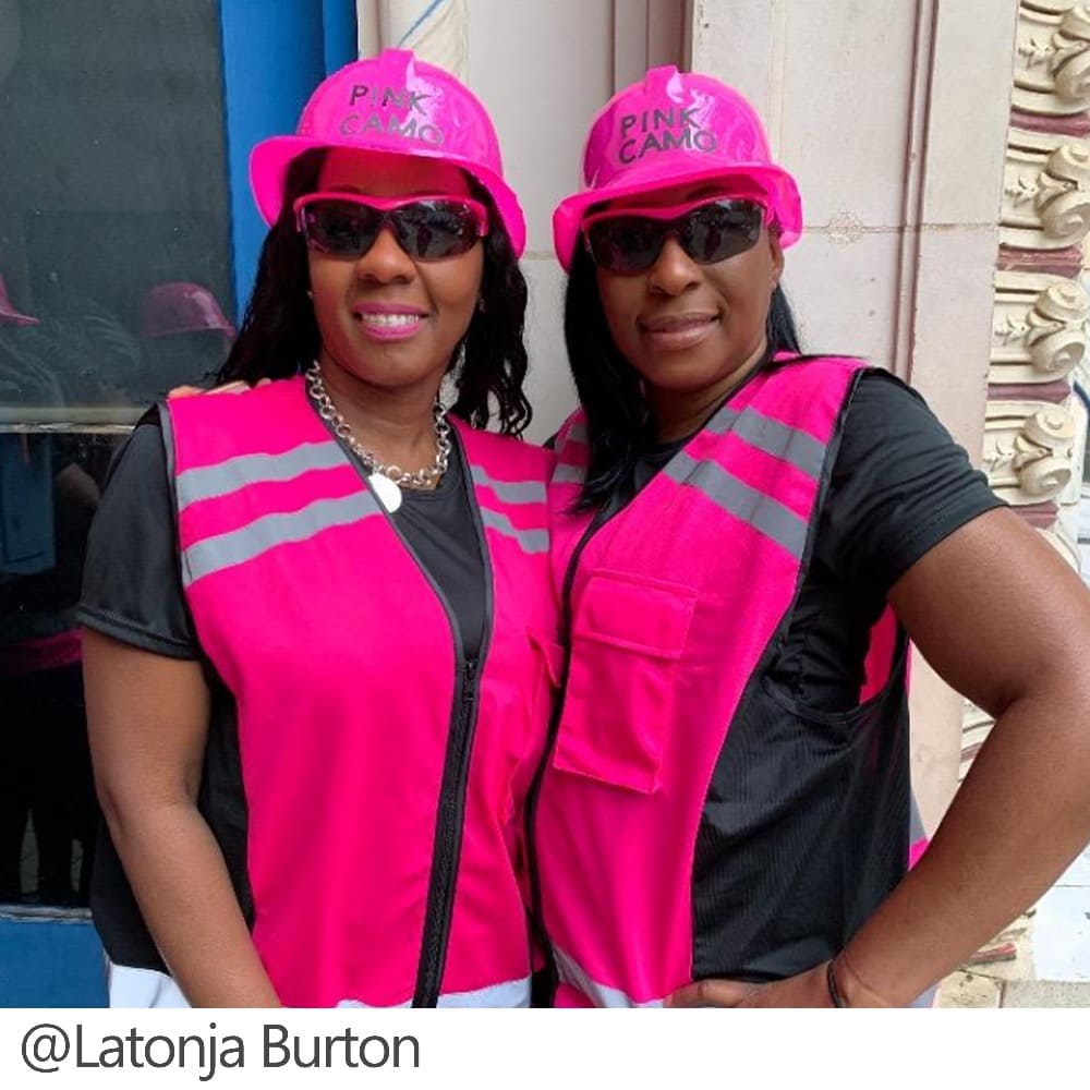 Two women wearing pink safety vests and hats.