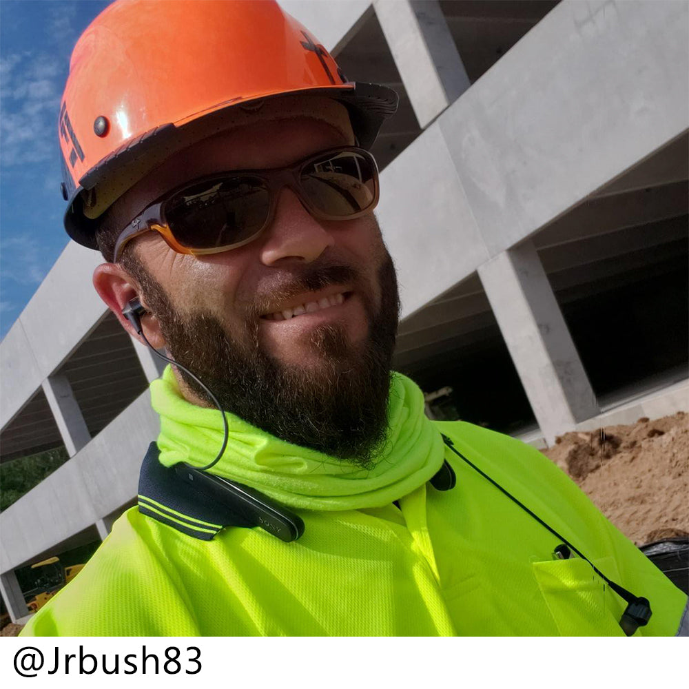 Man wearing an orange hard hat and bright yellow shirt with a construction site background
