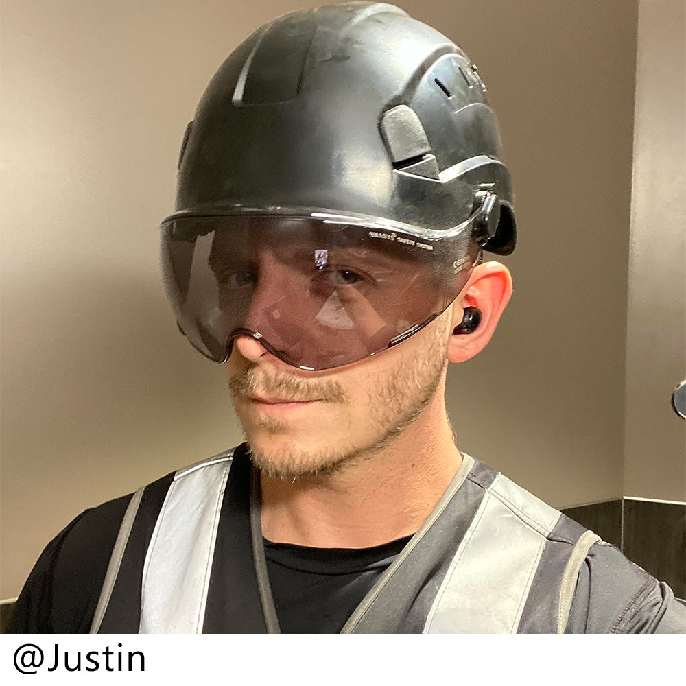 Person wearing a helmet with visor and safety vest indoors