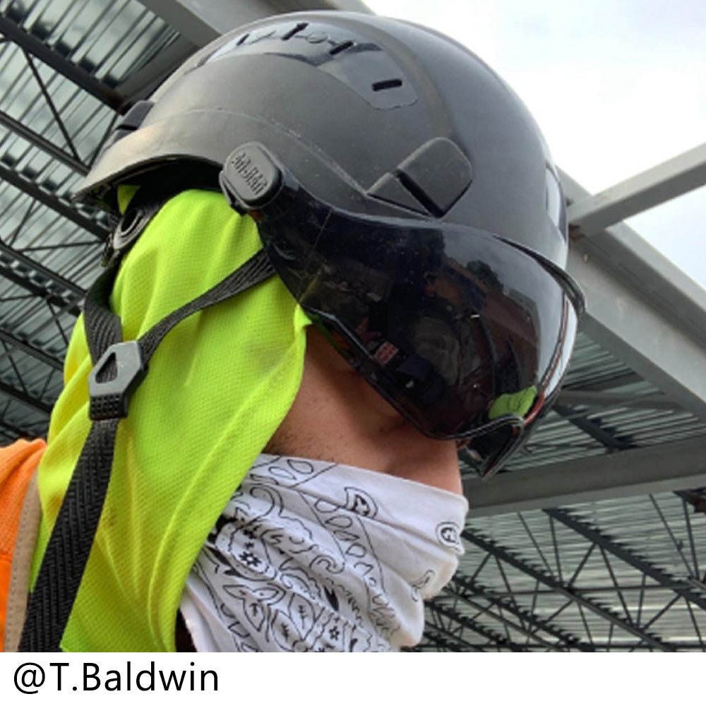 Person wearing a helmet and high-visibility vest in an industrial setting